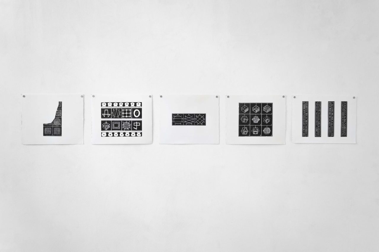 A series of 5 lino prints in landscape orientation hung on a white wall with silver magnets in the top two corners. The black and white prints display fragments of diagrams, repeated geometric patterns and numbered sequences.