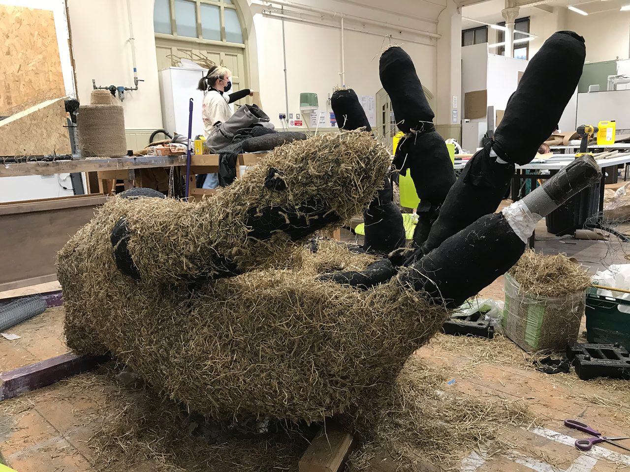 Photograph of the building process of the hand. Side view showing the straw and scaffolding layers underneath the wicker.