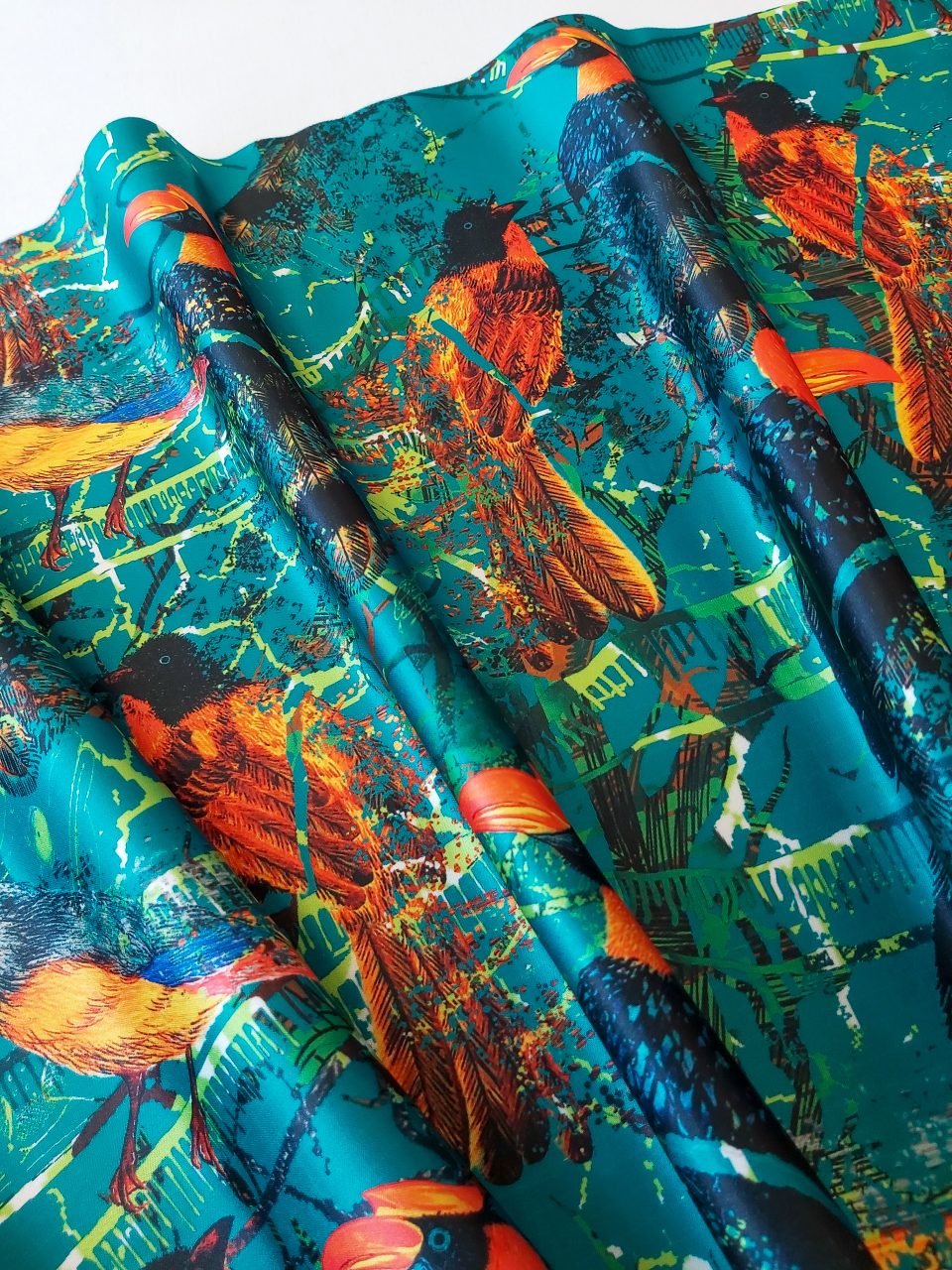 Vibrant image of printed fabric with bird and forest motifs